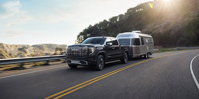 2024 GMC Sierra 1500 pulling a trailer on a highway road