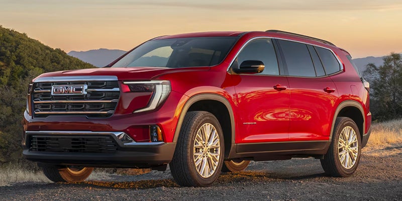 Red GMC Acadia parked outdoors with a scenic backdrop.