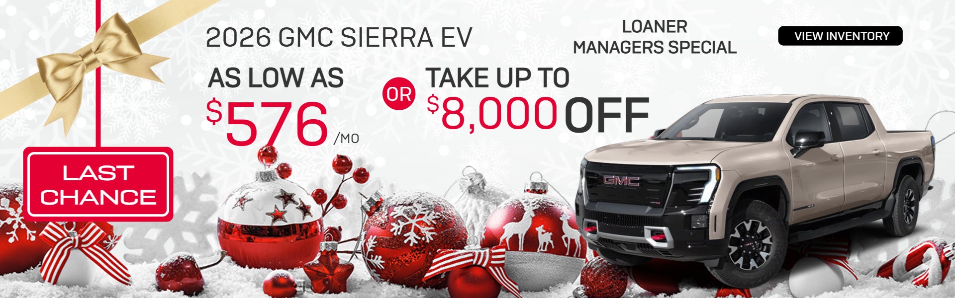 Two GMC pickup trucks, one white and one black, parked in a rocky desert with mountains in the background.