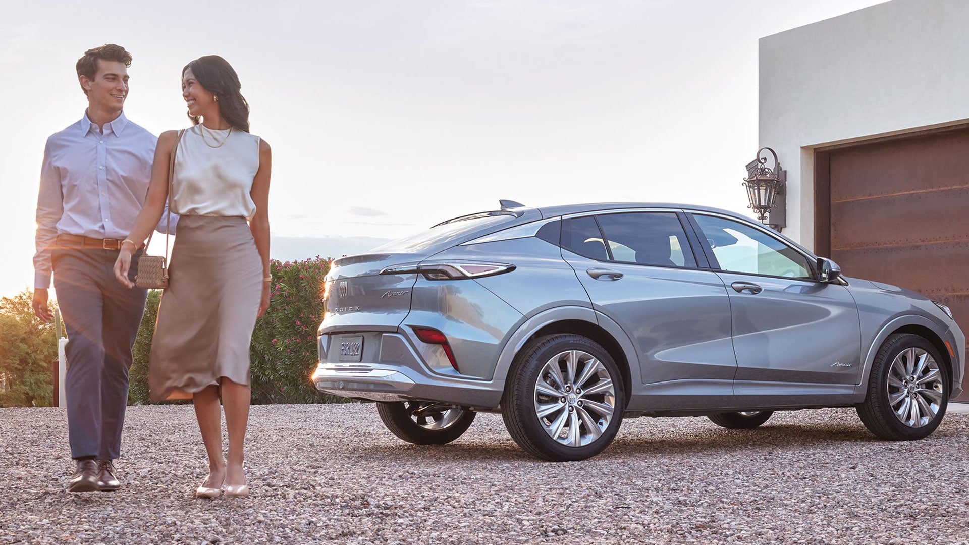 A Couple Walking Away from a Parked Silver Buick Envista Avenir