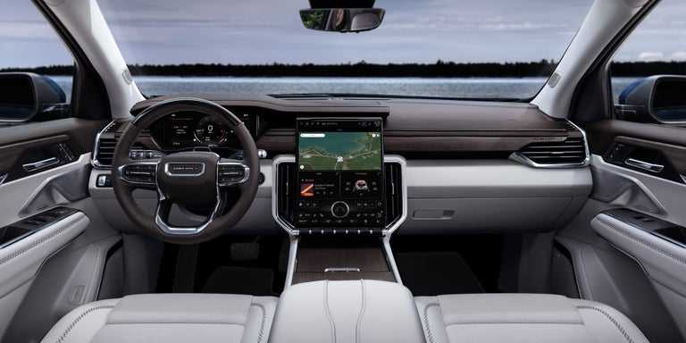 View of the GMC Acadia's White Interior and View of the Steering Wheel and Infotainment System