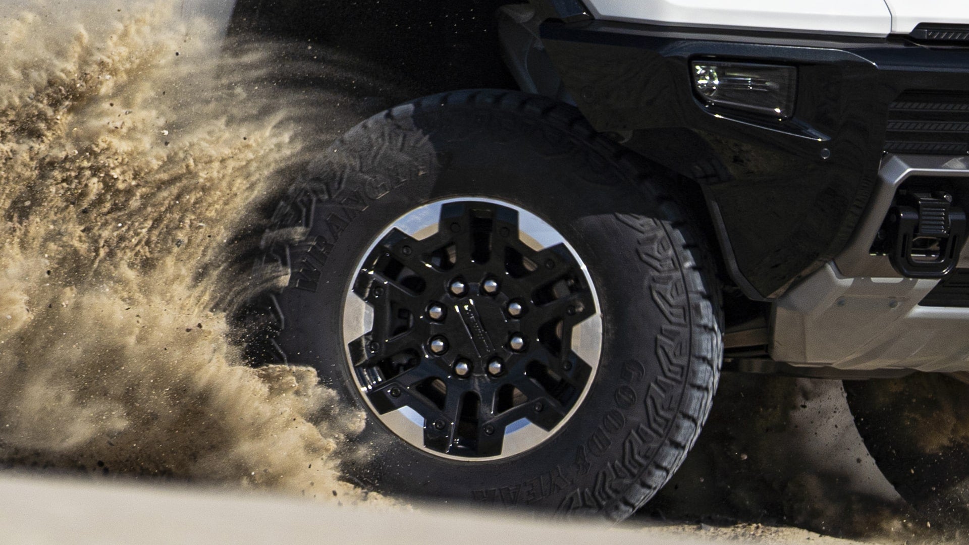 Close-up of GMC HUMMER EV Electric Truck tire spinning sand off-road