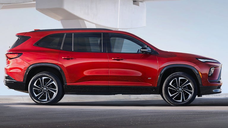 Side View of a Red 2025 Buick Enclave ST Under a Bridge